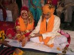 De bruidegom en bruid brengen een offer tijdens een hindoeïstische huwelijksceremonie in Rajasthan