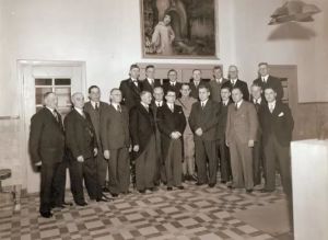 Op deze foto uit 1939 staat Anton Brejaart (vooste rij, vijfde van rechts, met handen voor het lichaam) met zijn collega's in de hal van het gemeentehuis. Deze foto is gemaakt op de plaats waar Brejaart vijf jaar later, rechts voor de trapleuning, doodgeschoten werd.