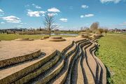 C Natuurpark De Veste In het zuiden van Waspik bevond zich een unieke plek waar het land niet zomaar onder water gezet kon worden. Hier lag namelijk een hogere zandrug, een zwak punt in de verdedigingslinie. Menno van Coehoorn, een militair ingenieur, ontwierp daarom een versterking genaamd het ‘Retranchement bij Waspik’ of ‘De Vest’. Dit verdedigingswerk werd in 1701 aangelegd tijdens de Spaanse Successieoorlog. Het bestond uit een zigzagvormige aarden wal met twee lunetten en twee redoutes. Na de oorlog raakte het retranchement in verval, maar het werd herhaaldelijk opgeknapt. Uiteindelijk verdween het in 1880. In 2008 is De Vest teruggebouwd. Aarden wallen werden opgebouwd om de contouren van de voormalige vestingwerken weer te geven. Daarbij is de bestaande gracht uitgegraven en vergroot. In 2009 is het park geopend.