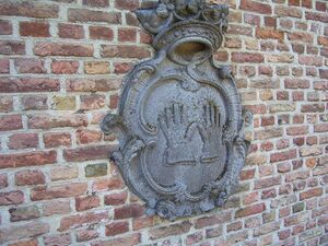 Wapenschild met het gemeentewapen van Raamsdonk, bestaande uit twee naast elkaar staande handschoenen. Vanaf 1654 werd het wapen met twee zilveren handschoenen op een zwarte achtergrond, gedekt met een gouden kroon met vijftien (later zeventien) parels, gebruikt voor de ambachtsheerlijkheid Raamsdonk.