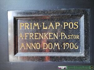 gedenksteen met tekst: "PRIM.LAP.POS./ A. FRENKEN - PASTOR/ ANNO DOM. 1900"