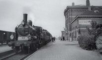 station Geertruidenberg - stationsgebouw (1950) - Hoog middendeel (met gekanteelde borstwering) en twee lage vleugels - Perronzijde met trein en personeel.